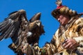 Eagle Hunter at traditional clothing, while hunting to the hare holding a golden eagle, in mountains western Mongolia.