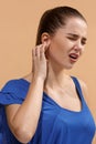 The Ear ache. The sad woman with headache or pain on a blue studio background. Royalty Free Stock Photo