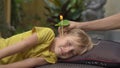 Ear candling being carried out on a little boy in a spa in a tropical garden