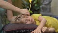 Ear candling being carried out on a little boy in a spa in a tropical garden