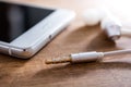 In-Ear Headphones And Cable Lying Next To A White Mobile Phone On Wooden Table Royalty Free Stock Photo