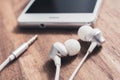 In-Ear Headset And It`s Cable Lying In Front Of A White Smartphone`s Headphone Jack Royalty Free Stock Photo