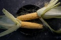 ear of ripe corn with tops on a black plate