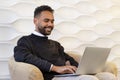 earded young man using laptop, sitting on couch at home, handsome guy having video call online in social network, having fun. Royalty Free Stock Photo