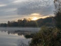 Early autumn morning, white mist over water and ground, beautifully colored and blurred tree silhouettes Royalty Free Stock Photo