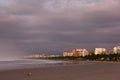 Early on beach. City buildings and cloudy sky. Foggy sea and empty beach. Royalty Free Stock Photo