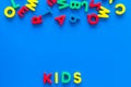 Early childhood development concept. Word kids written by plastic letters of toy alphabet on blue background top view