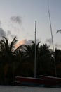 Early evening on the shores of the Indian Ocean, red boats with masts against the backdrop of palm trees and a blue sky with Royalty Free Stock Photo