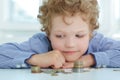 Early financial education concept. Boy looking at a stack of coins.