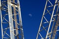 Early moon in cobalt sky ,nestled between two crane booms