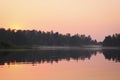 Early morning, calm water surface, fog over the lake. Summer landscape. Royalty Free Stock Photo