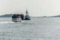 Early morning commuter ferry coming across Boston Harbor to dock passing big freight ship with tugboat Royalty Free Stock Photo