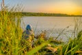 Early morning , a fisherman sits on the pier with fishing rods for fishing on the lake. Shore of the lake during sunset. Royalty Free Stock Photo