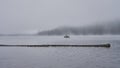 Early morning fishing from a small boat on a lake on a foggy fall day. Royalty Free Stock Photo