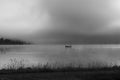 An early morning at Lac de Joux, Switzerland: A lone fisherman on a boat, fog is still hiding the rising sun Royalty Free Stock Photo