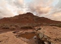 Early morning light makes the clouds glow softly after a winter rain has left a pool of water on top of a boulder Royalty Free Stock Photo