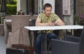 Early morning lonely tired Serious hipster tourist man holding mobile phone in cozy cafe interior