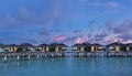 Early morning in the Maldives. Water villas are standing over a calm aquamarine ocean Royalty Free Stock Photo