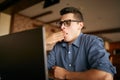 Early morning in the office. Sleepy tired handsome hipster freelancer in glasses is yawning at his work place in front Royalty Free Stock Photo