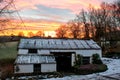 Early morning snowy barn with a vibrant orange sunrise behind it. Royalty Free Stock Photo