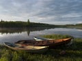 Dawn. Three boats are moored on the shore of the lake.