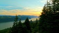 Early morning sunrise aerial rising up from behind trees revealing road, Vista House, oranges & yellows reflecting off the river