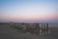 Early morning sunrise overlooking the ocean with rocks and wooden barricade