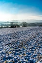 Early morning view across a snow covered ploughed field to distant misty hills in the Cotswolds, Gloucestershire, UK Royalty Free Stock Photo