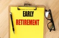 EARLY RETIREMENT text on yellow paper on clipboard with pen and glasses Royalty Free Stock Photo