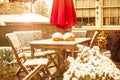 Early snow - outdoor table and chairs with two jack o lanterns and a sun umbrella on a patio during a snow shower with house Royalty Free Stock Photo