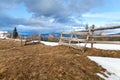 Wooden gate on snowcovered pasture, ark clouds over mountains. Royalty Free Stock Photo