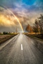 Early spring landscape with dramatic sky, rainbow and road lines Royalty Free Stock Photo