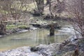 Early spring landscape with a small wild river, bare trees, reflections in the water, dry grass on the banks of the Royalty Free Stock Photo