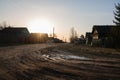 In the early spring morning in the village, the sun shines on the dirt road and wooden houses. Royalty Free Stock Photo