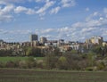 Early spring Prague landscape with high-rise apartment building, brown field, green grass, trees with fresh lush leaves and blue Royalty Free Stock Photo