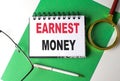 EARNEST MONEY text on notebook on green paper