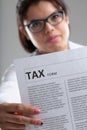 Earnest woman wearing glasses holding a Tax form