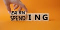 Earning and Spending symbol. Businessman hand. Turned cubes with words Earning and Spending. Beautiful orange background. Business