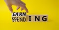 Earning and Spending symbol. Businessman hand. Turned cubes with words Earning and Spending. Beautiful yellow background. Business