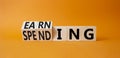 Earning and Spending symbol. Turned cubes with words Earning and Spending. Beautiful orange background. Business and Earning and