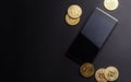 Earnings on crypto-currencies: gold coins bitcoin and smartphone on a dark background. Horizontal frame.