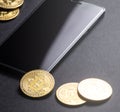 Earnings on crypto-currencies: gold coins bitcoin and smartphone on a dark background. Square frame. Royalty Free Stock Photo