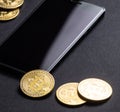 Earnings on crypto-currencies: gold coins bitcoin and smartphone on a dark background. Square frame. Royalty Free Stock Photo