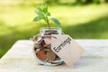 Earnings. Glass jar with coins, on a wooden table, on a natural background.