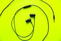 Earphones lying on the green background. Modern music concept. Audio technology