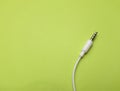 Earphones Mini Jack plug on green background Royalty Free Stock Photo