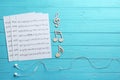 Earphones, music notes and sheets on wooden background, flat lay. Royalty Free Stock Photo