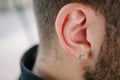 Earring in the male ear. Piercing Part of the body Royalty Free Stock Photo