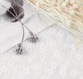 Grey pendant flower earrings in the shape of a flower.Earrings are flanked by cardboard, floral specimens and other ornaments