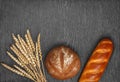 Ears of wheat, freshly baked bread and a loaf on wooden background. Royalty Free Stock Photo